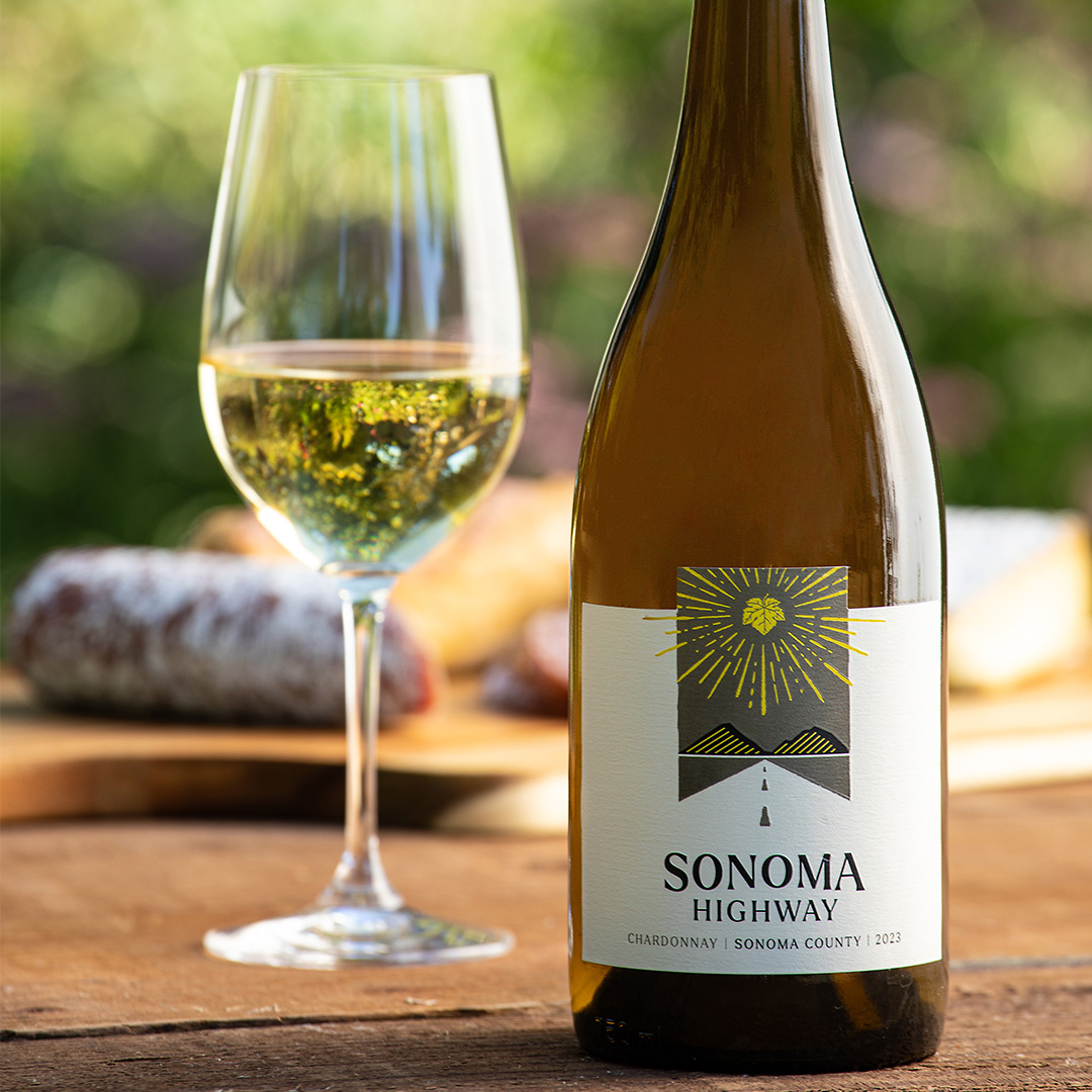 Photo of Sonoma Highway Chardonnay bottle on a table with poured glass and cheese tray